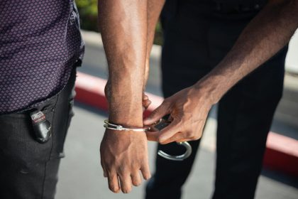 Close-up of a police officer handcuffing a suspect outdoors, enforcing law.