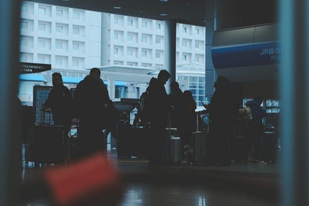 Silhouetted travelers wait with luggage in a Japanese railway station, focusing on transportation and travel.