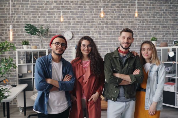 A cheerful group of young professionals smiling confidently in a modern office setting.